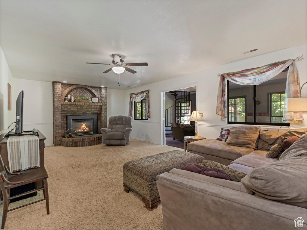 Carpeted living area featuring ceiling fan and a fireplace