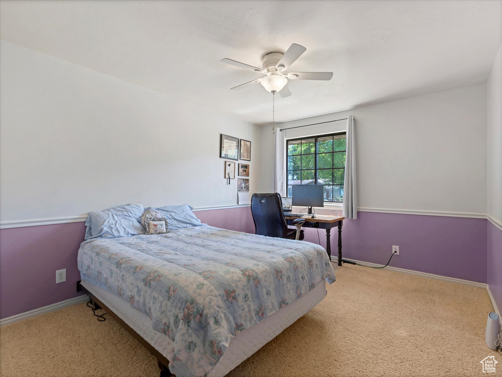 Carpeted bedroom with baseboards, ceiling fan, and a desk