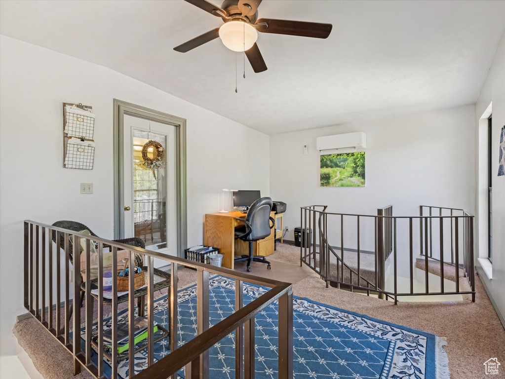 Office space with an AC wall unit, carpet floors, and ceiling fan