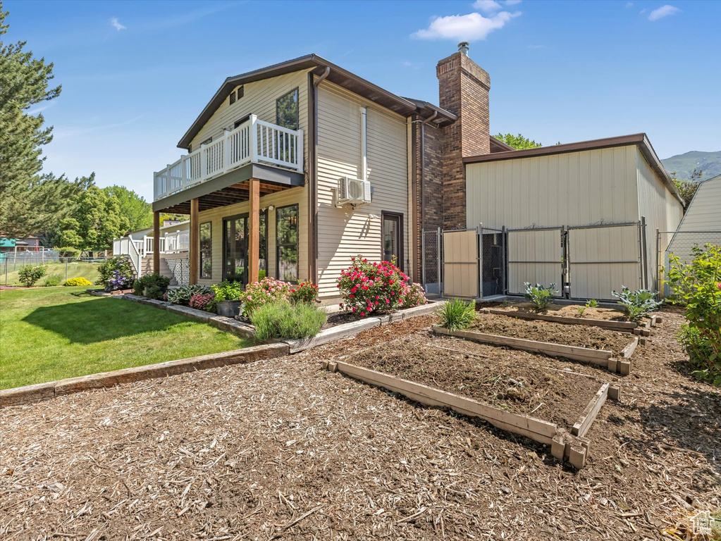 Back of house featuring a garden, a chimney, a balcony, and cooling unit