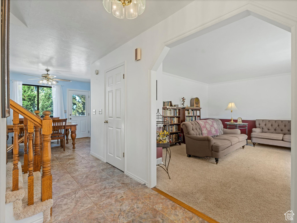 Living area with arched walkways, a chandelier, ceiling fan, and baseboards