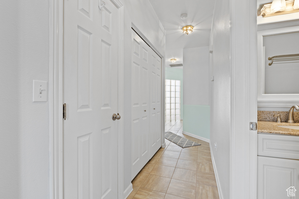 Corridor with a sink, light tile patterned floors, and baseboards