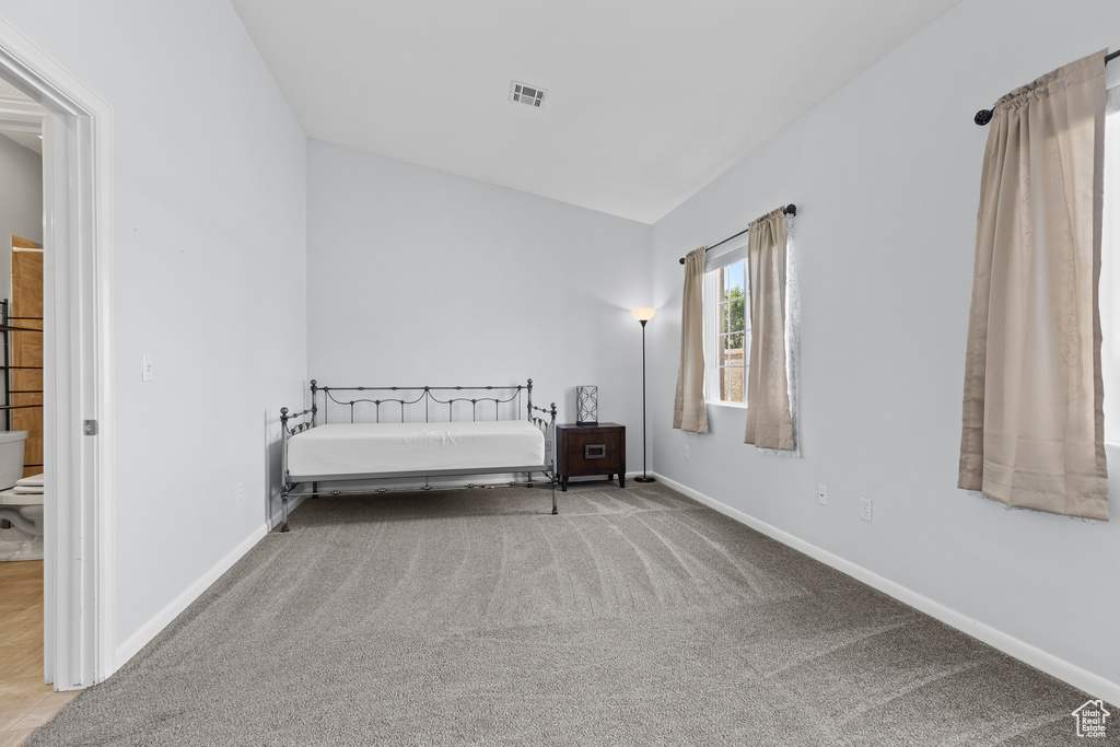 Bedroom with carpet flooring, baseboards, and vaulted ceiling