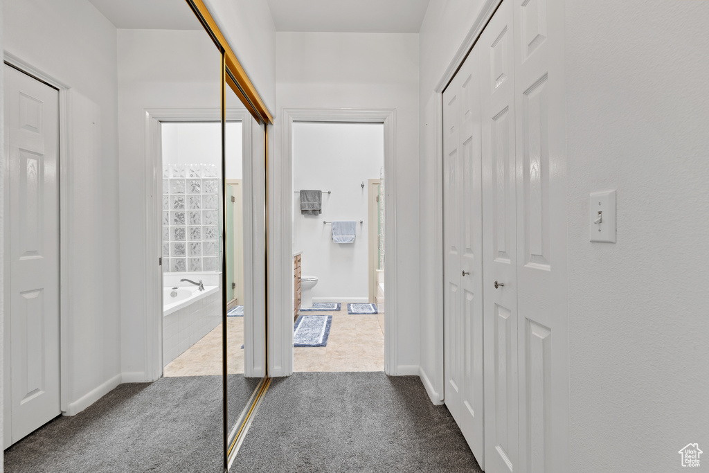 Hall with dark colored carpet and baseboards