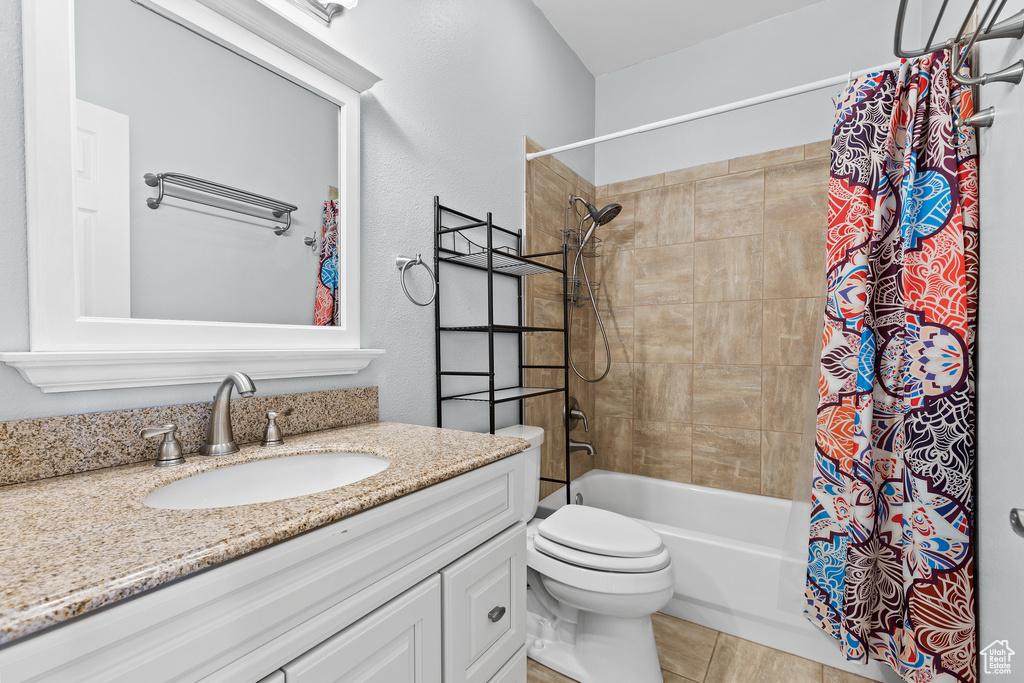 Bathroom with shower / bath combination with curtain, vanity, and toilet