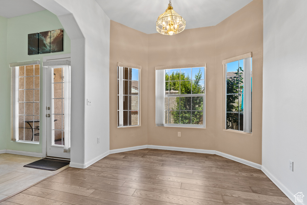 Foyer entrance with a chandelier, hardwood / wood-style floors, baseboards, and arched walkways