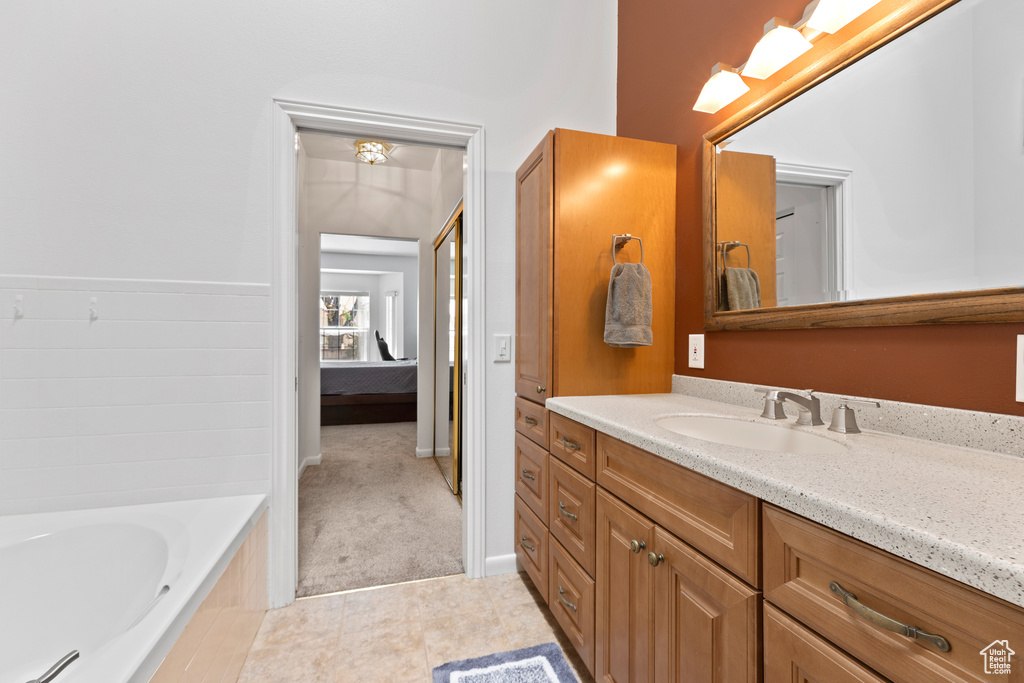 Full bathroom with vanity, a relaxing tiled tub, and tile patterned flooring