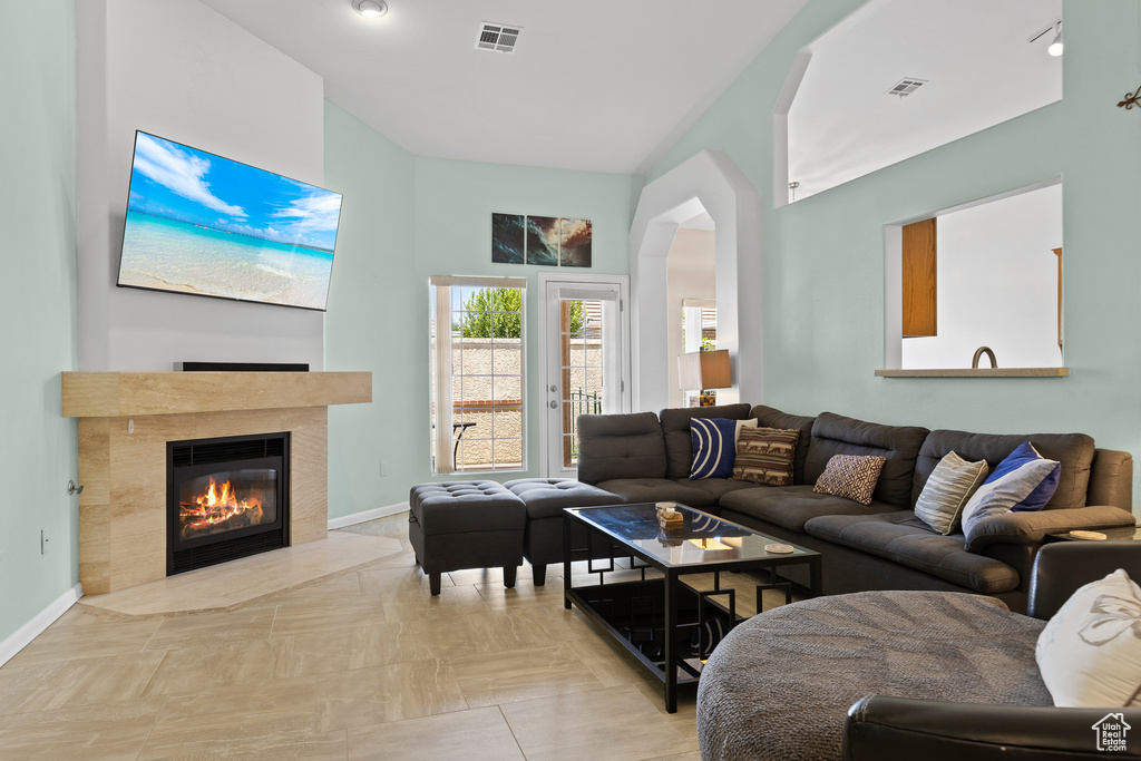 Living room with a tiled fireplace, baseboards, and arched walkways