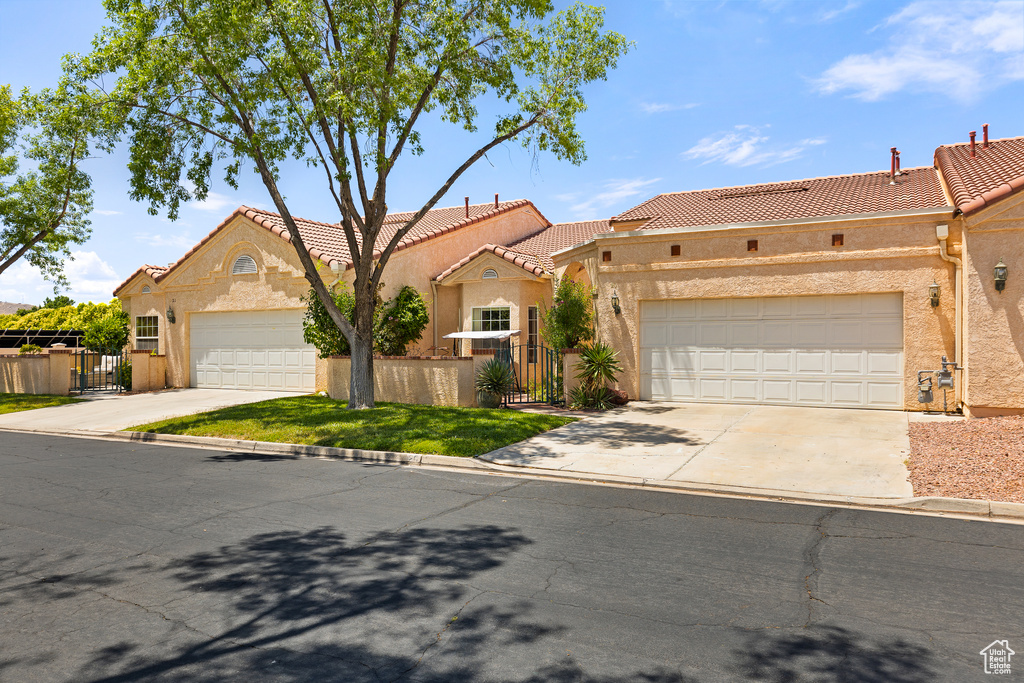 View of front facade with driveway, stucco siding, a tiled roof, and a garage