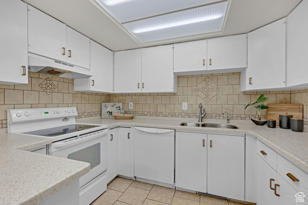 Kitchen featuring white appliances, under cabinet range hood, a sink, light countertops, and light tile patterned floors