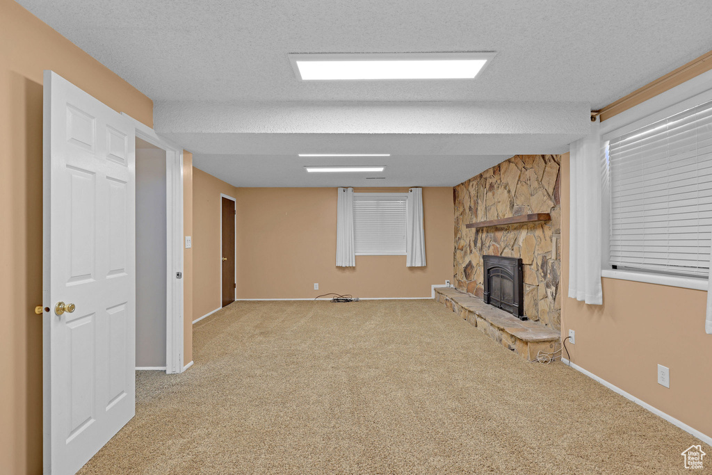 Unfurnished living room featuring carpet, baseboards, and a textured ceiling