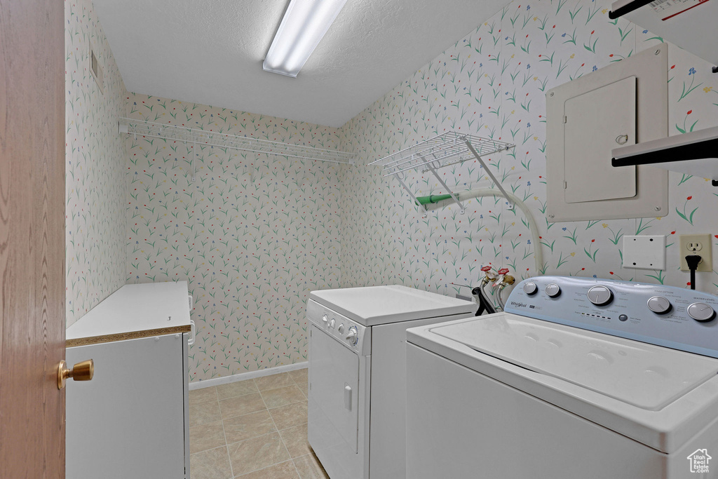 Laundry area with washer and dryer, wallpapered walls, light tile patterned floors, and baseboards