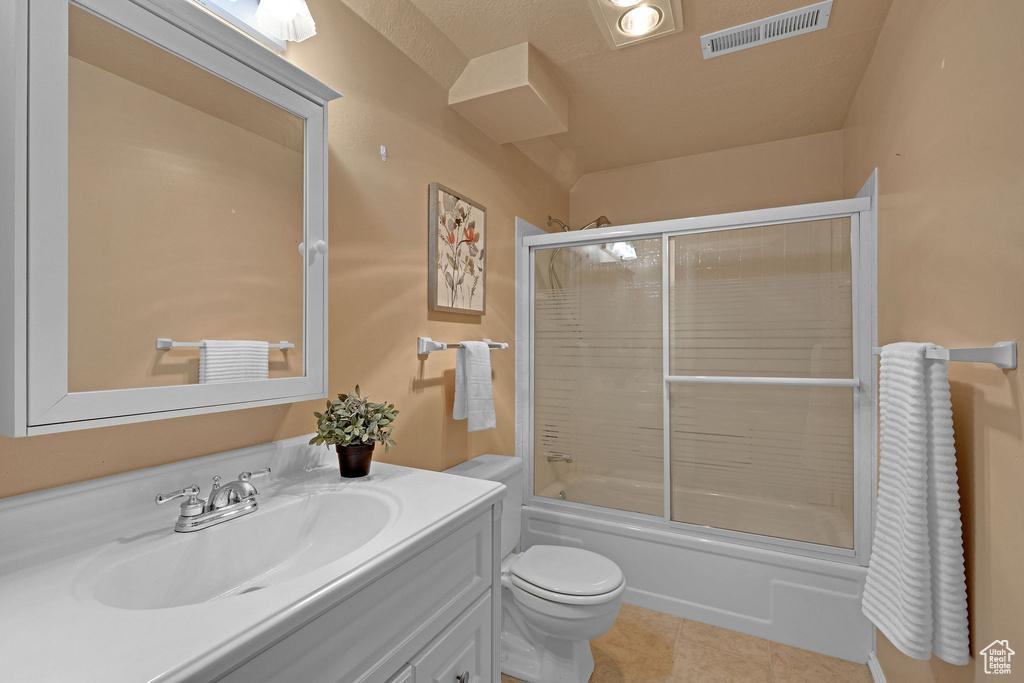 Full bath with vanity, toilet, tile patterned floors, and combined bath / shower with glass door