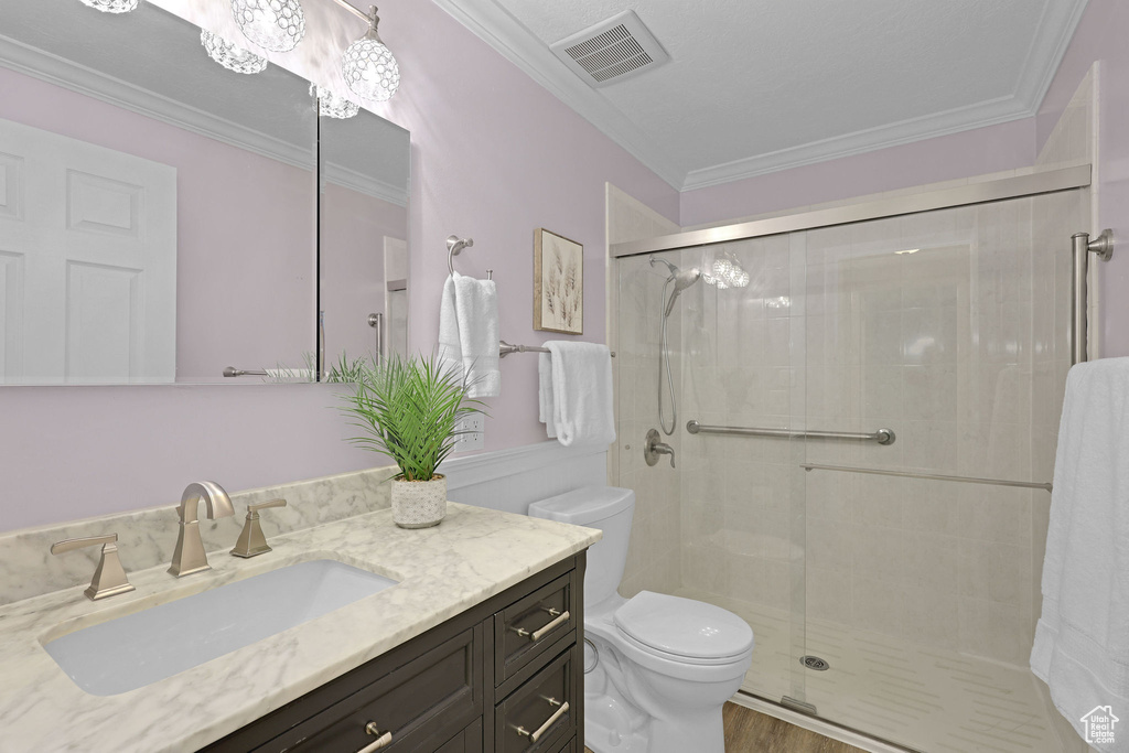 Bathroom featuring toilet, vanity, a shower stall, ornamental molding, and wood finished floors