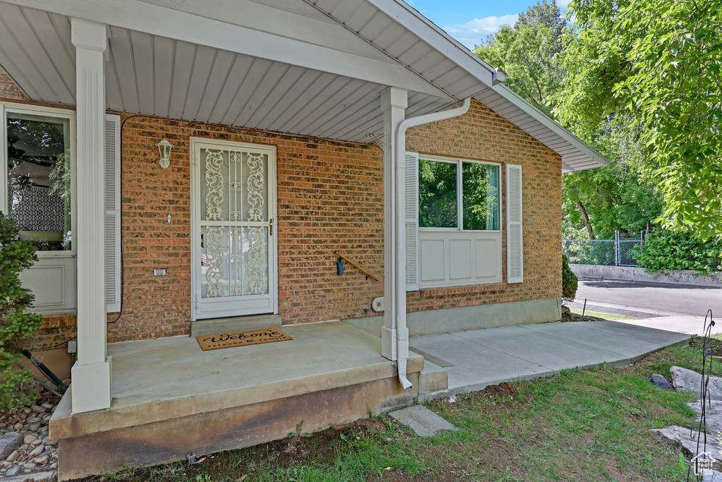View of exterior entry featuring brick siding and covered porch