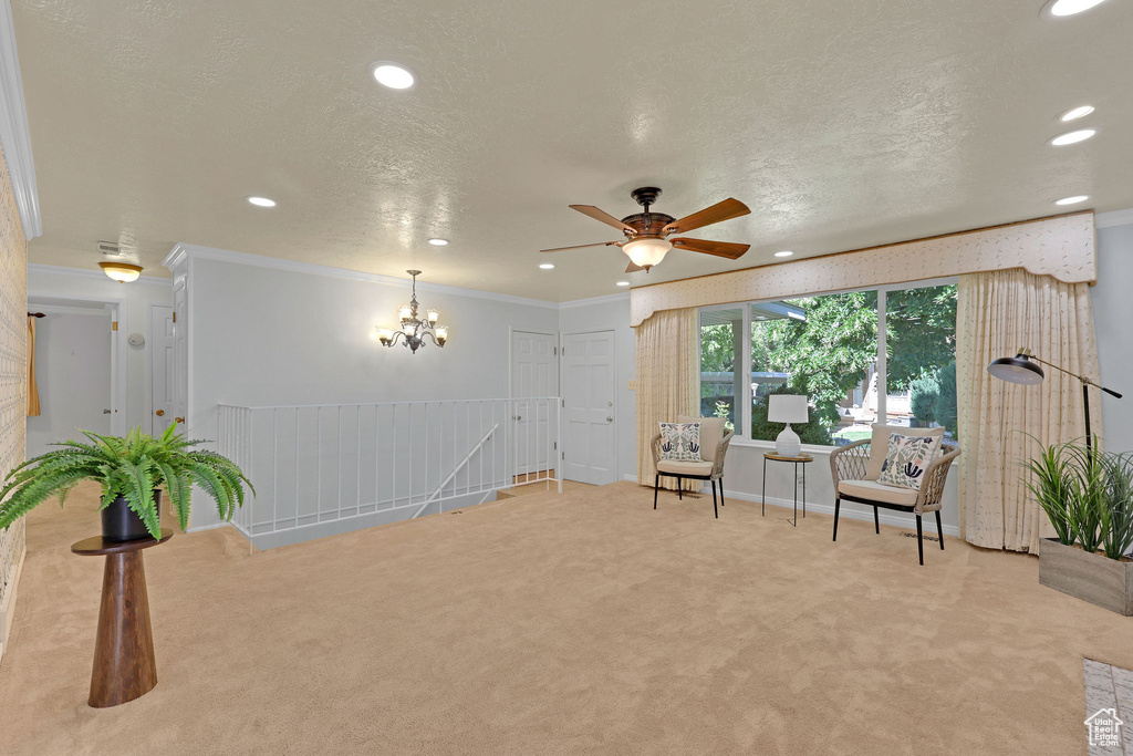 Living area with carpet floors, recessed lighting, ceiling fan, crown molding, and a chandelier