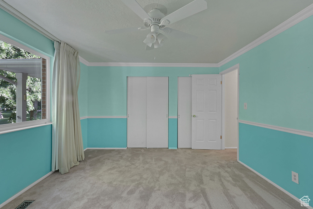 Unfurnished bedroom with carpet floors, a closet, a ceiling fan, ornamental molding, and baseboards