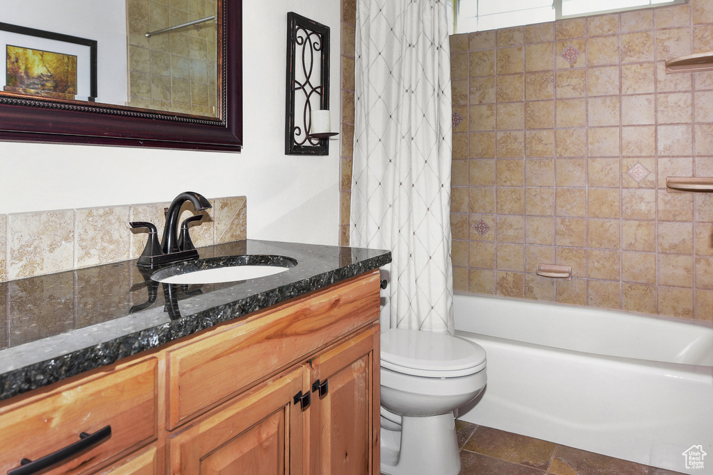 Bathroom featuring toilet, vanity, and shower / bath combo with shower curtain