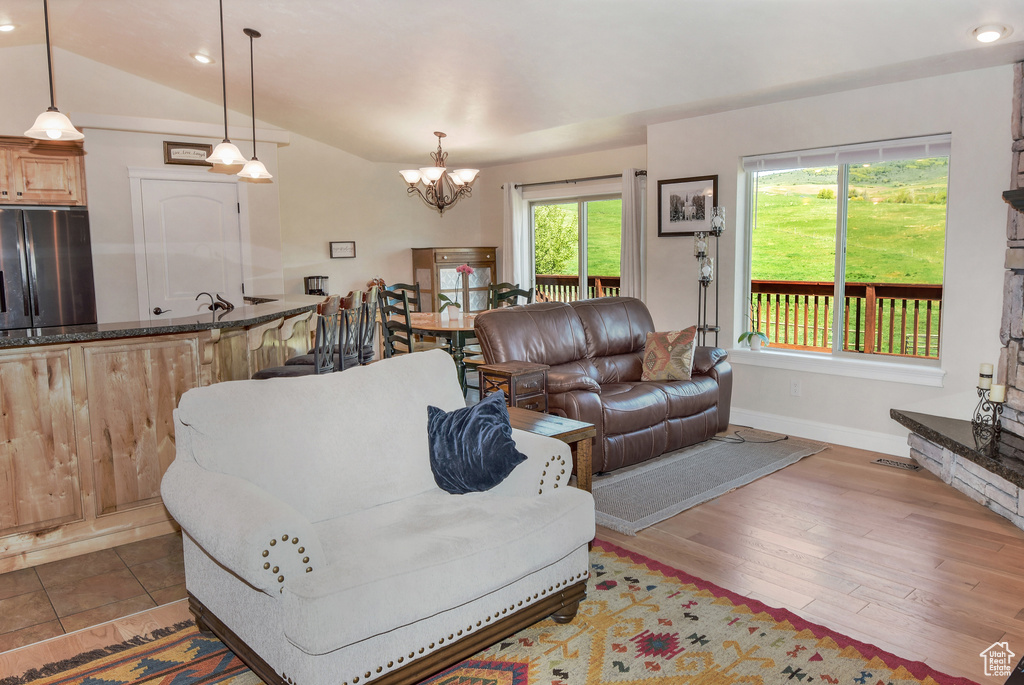 Living area with a chandelier, baseboards, recessed lighting, wood finished floors, and vaulted ceiling
