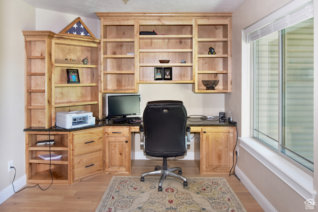Office space featuring built in desk, light wood-type flooring, and baseboards