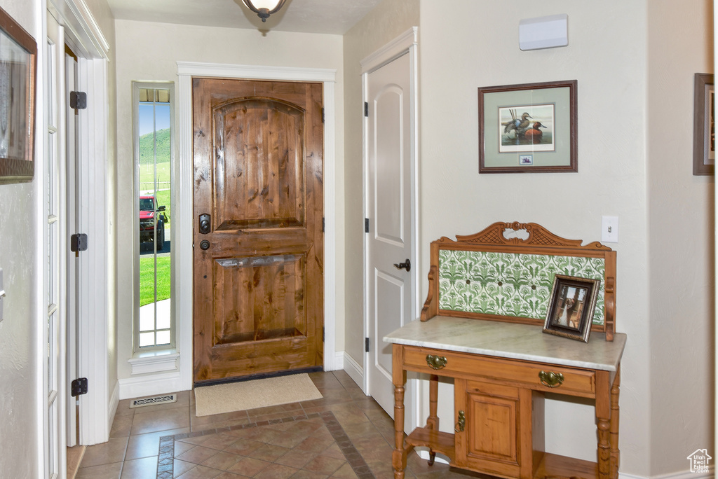 Foyer entrance with inlaid floor details, baseboards, healthy amount of natural light, and tile patterned floors