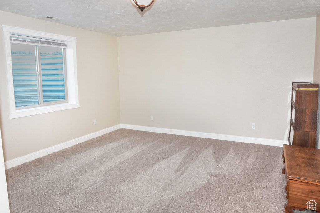 Carpeted spare room featuring baseboards and a textured ceiling