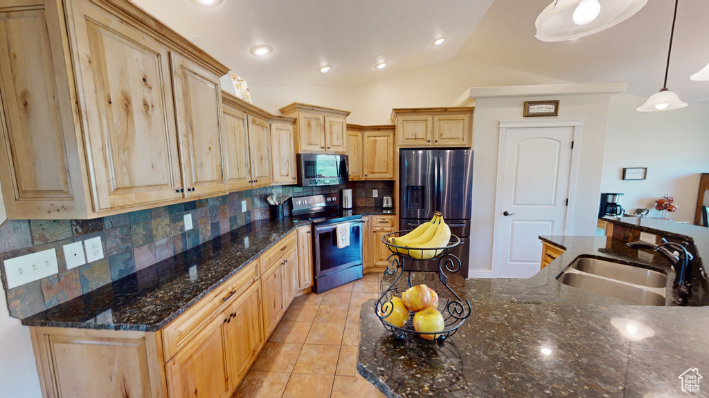 Kitchen featuring stainless steel appliances, light tile patterned flooring, decorative backsplash, light brown cabinets, and lofted ceiling