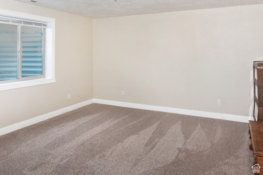 Carpeted empty room featuring baseboards