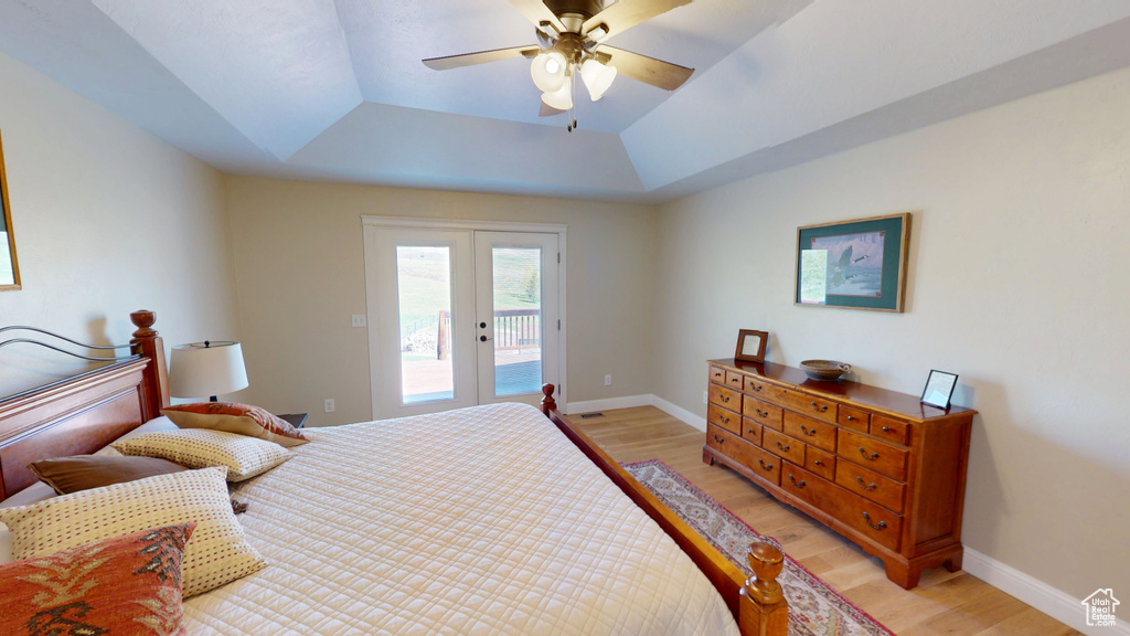 Bedroom featuring access to outside, a raised ceiling, light wood finished floors, and french doors