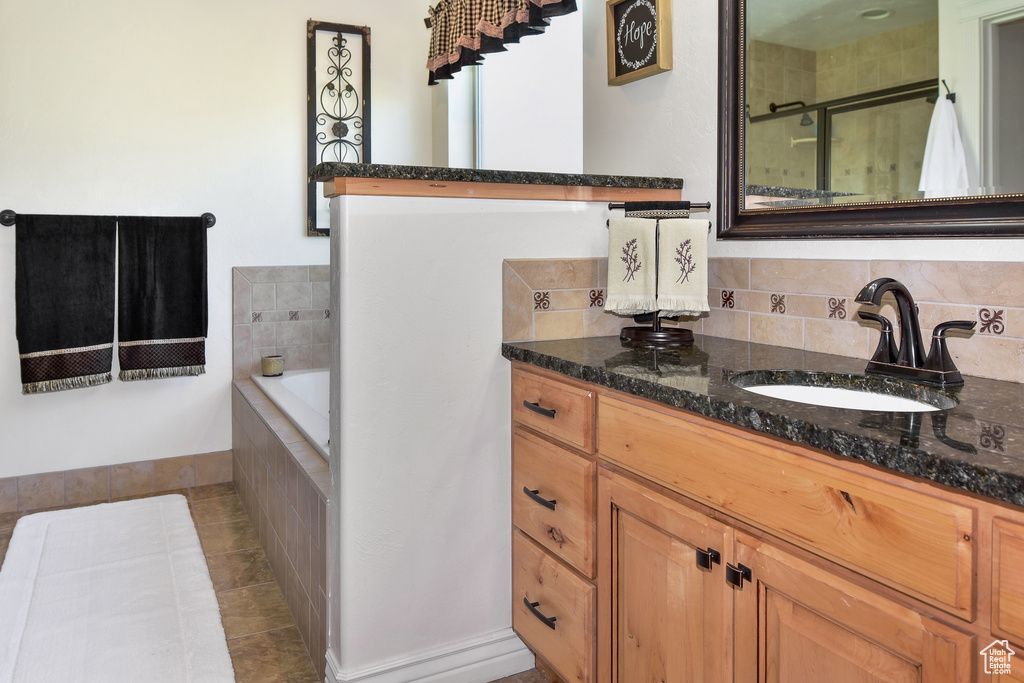 Full bath with tiled bath, a tile shower, vanity, tile patterned floors, and backsplash