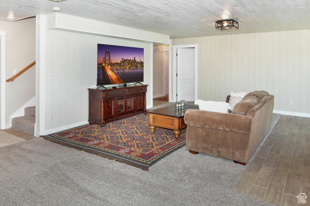 Living room with baseboards, stairway, wood finished floors, wooden walls, and wooden ceiling