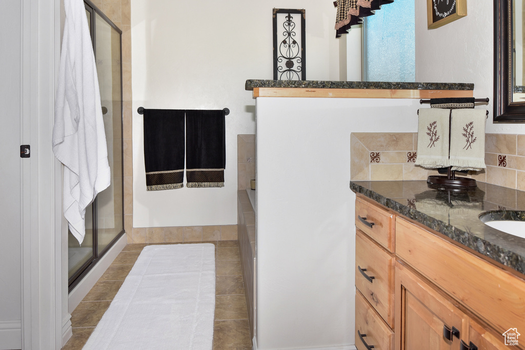 Full bath with a shower stall, backsplash, vanity, and tile patterned floors