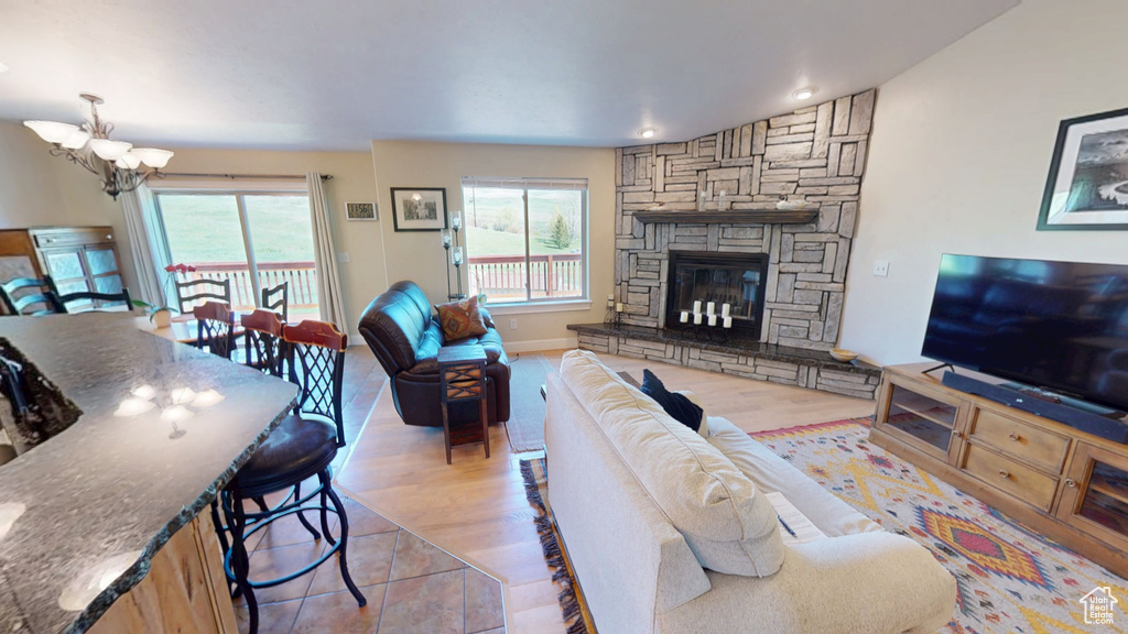 Living room with a chandelier, a stone fireplace, recessed lighting, and light wood-style flooring