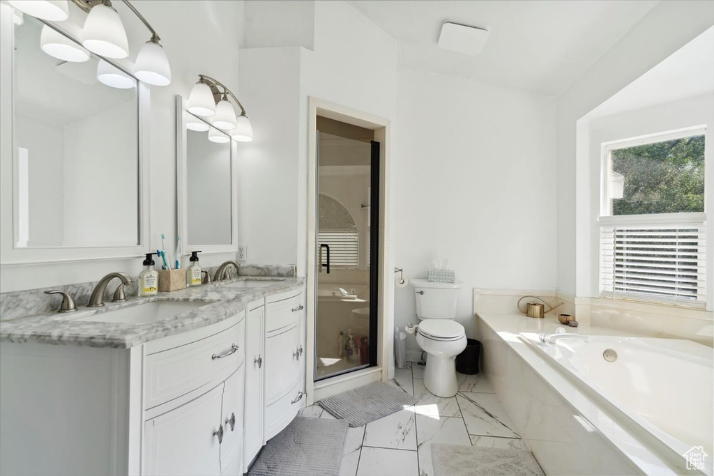 Full bath with a bath, toilet, double vanity, marble look tile flooring, and a stall shower