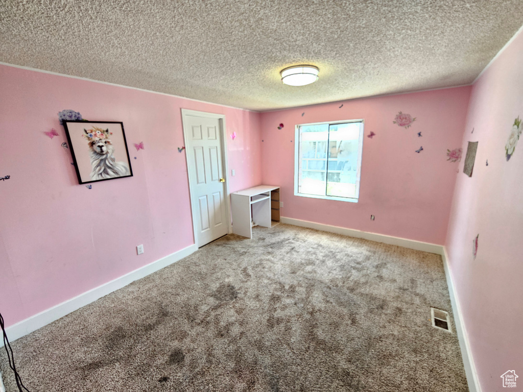 Unfurnished bedroom with light carpet, a textured ceiling, and baseboards
