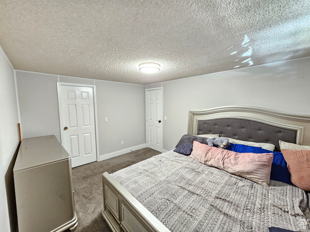 Carpeted bedroom featuring a textured ceiling and baseboards