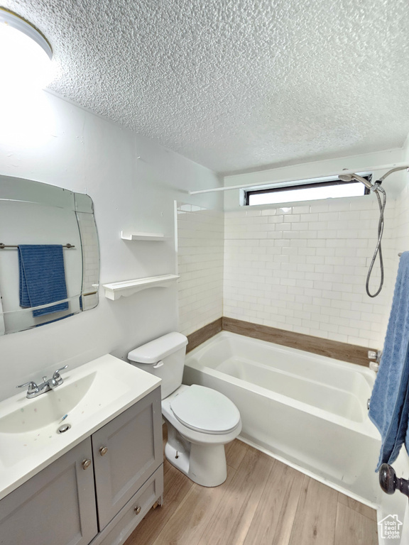 Full bathroom with a textured ceiling, vanity, bathtub / shower combination, wood finished floors, and toilet