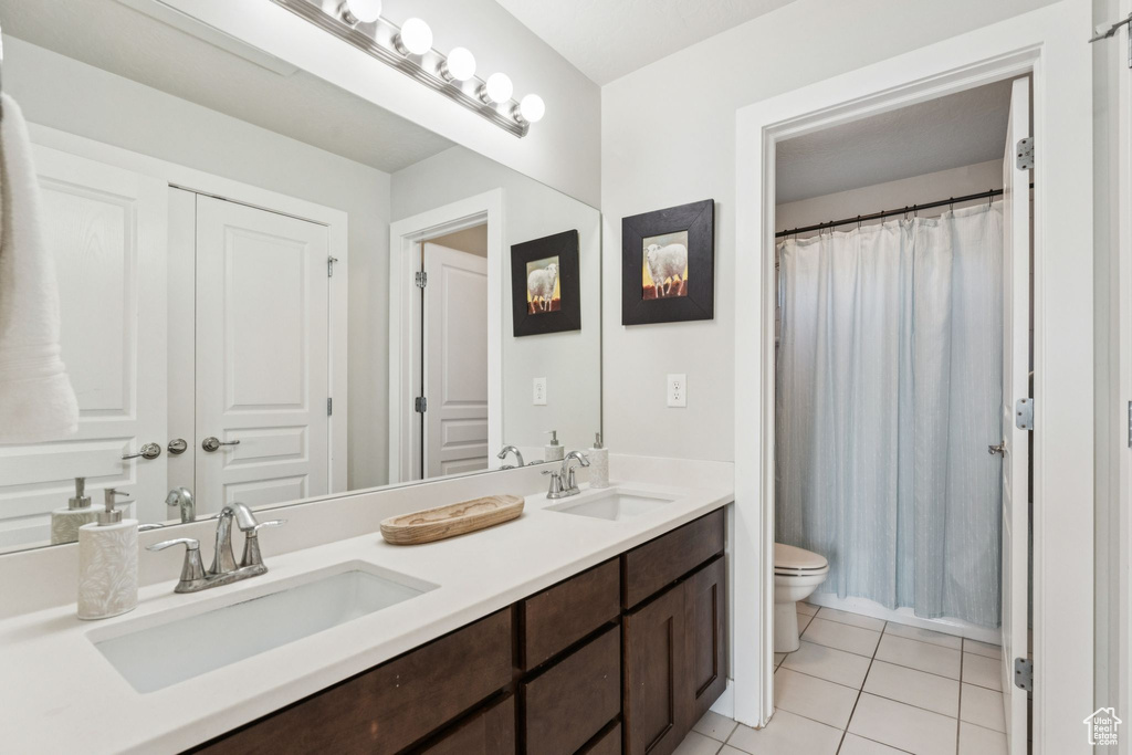 Bathroom with toilet, tile patterned flooring, double vanity, and curtained shower