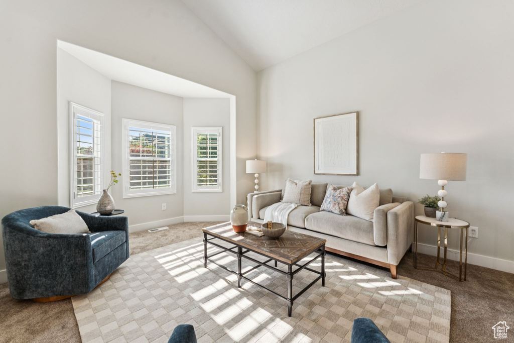 Living area with light colored carpet, baseboards, and lofted ceiling