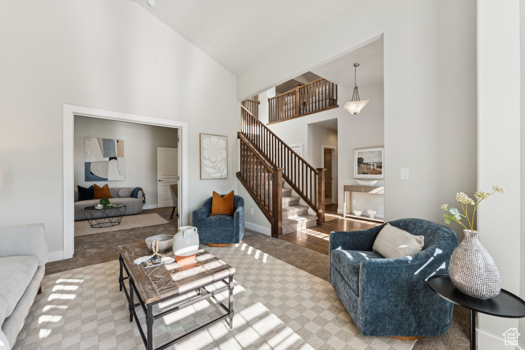 Living area featuring carpet floors, a towering ceiling, stairs, and baseboards