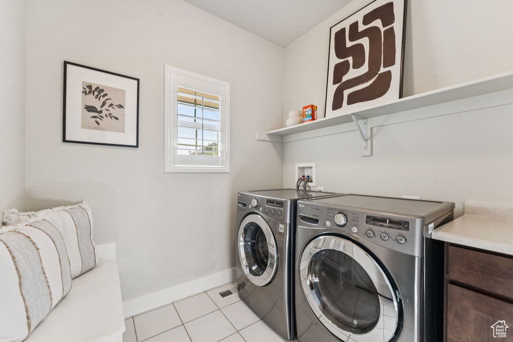 Washroom featuring washing machine and dryer, baseboards, and light tile patterned floors