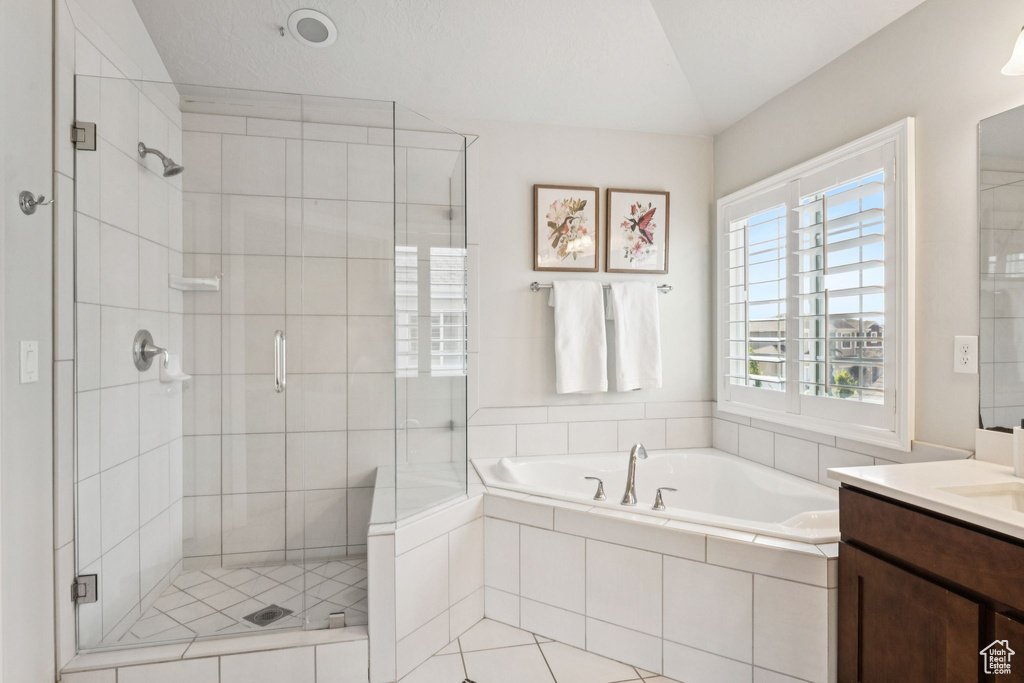 Full bathroom featuring vanity, a stall shower, a garden tub, and vaulted ceiling