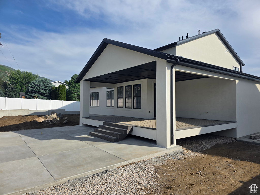 View of side of property featuring stucco siding, metal roof, and a patio area