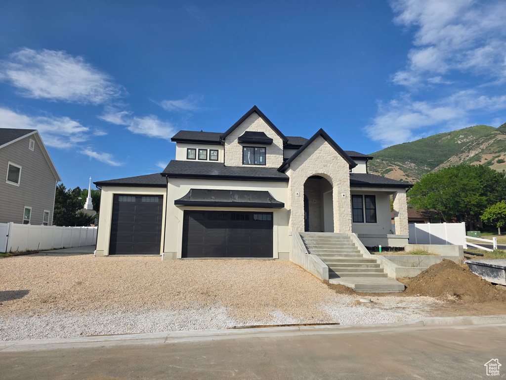 View of front facade with driveway, a mountain view, stone siding, stucco siding, and an attached garage