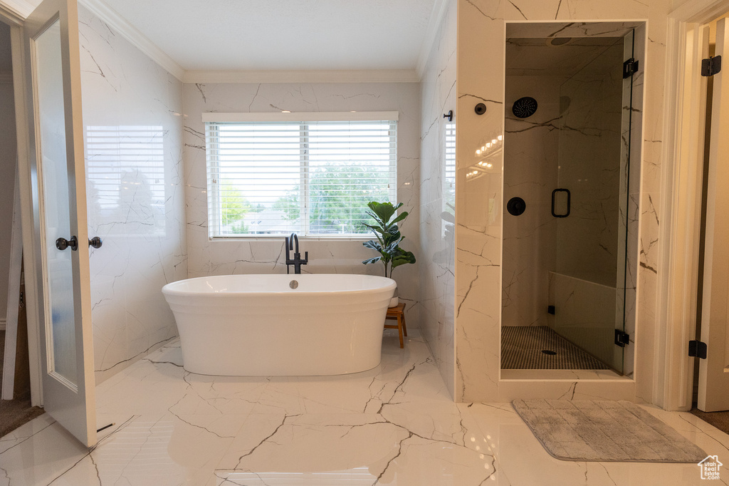 Full bath featuring a marble finish shower, crown molding, marble tiled flooring, and a soaking tub