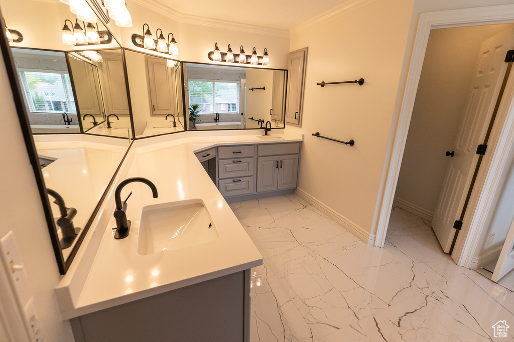 Bathroom featuring double vanity, crown molding, marble finish floors, and baseboards