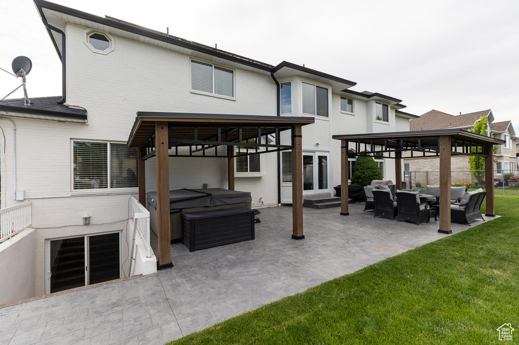 Back of property featuring a hot tub, an outdoor living space, a gazebo, and a patio
