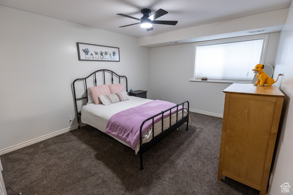 Bedroom with dark carpet, baseboards, and a ceiling fan