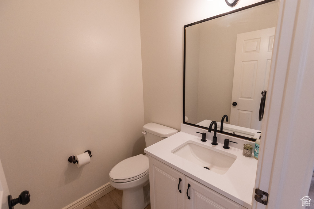 Bathroom with toilet, vanity, baseboards, and wood finished floors