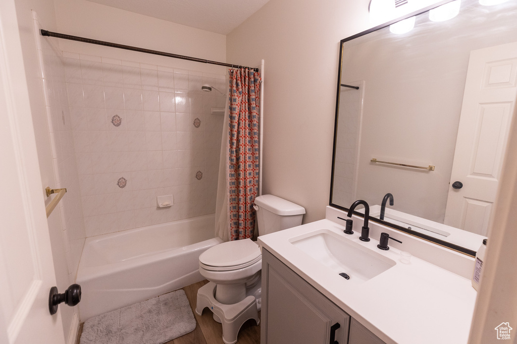 Bathroom with vanity, toilet, shower / bath combo, and wood finished floors